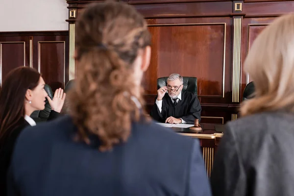 Procureur pointant avec la main tout en parlant au juge près homme flou et avocat — Photo de stock