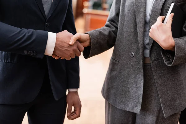 Visión parcial del hombre de negocios y abogado estrechando la mano en la corte - foto de stock