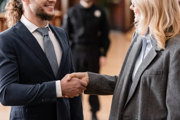 Cropped view of smiling advocate shaking hands with happy businessman in court — Stock Photo