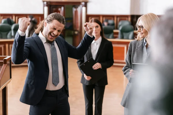 Aufgeregter Geschäftsmann brüllt und zeigt Win-Win-Geste in der Nähe von Anwalt vor Gericht — Stockfoto