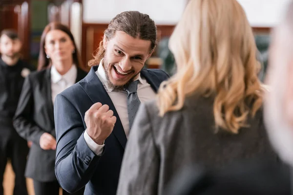 Selective focus of excited businessman showing win gesture near advocate and prosecutor in court — Stock Photo