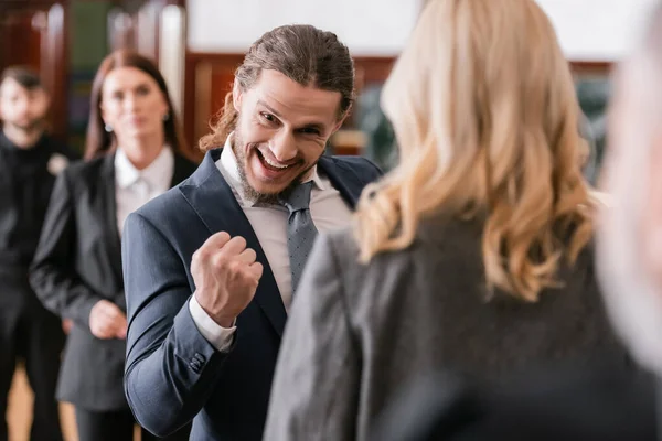 Foyer sélectif de l'homme d'affaires excité montrant geste gagnant près avocat et procureur au tribunal — Photo de stock