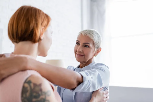 Smiling lesbian woman looking at tattooed girlfriend on blurred foreground — Stock Photo