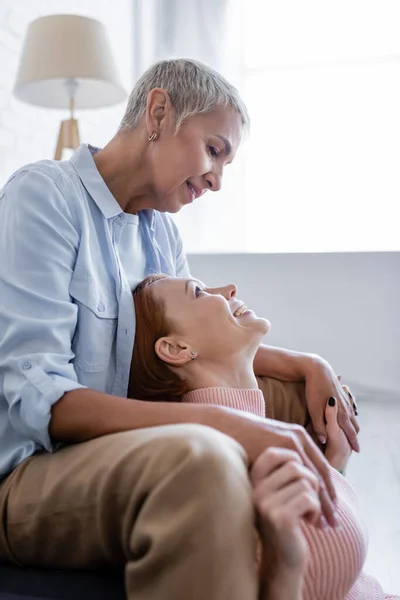 Seitenansicht lächelnder lesbischer Frauen, die sich an den Händen halten und einander anschauen — Stockfoto