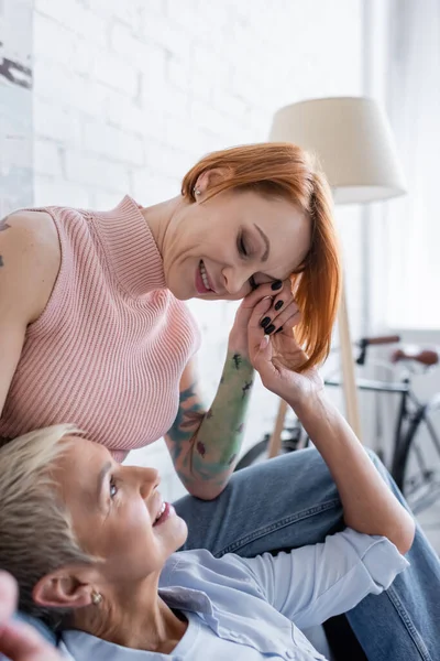 Happy same sex couple holding hands and looking at each other at home — Stock Photo