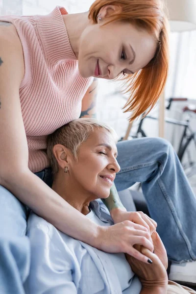 Frau umarmt lesbische Freundin zu Hause lächelnd mit geschlossenen Augen — Stockfoto