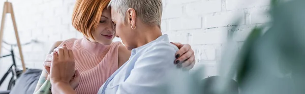 Coppia lesbica che si tiene per mano mentre siede faccia a faccia su primo piano sfocato, striscione — Foto stock