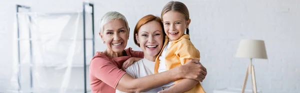 Happy same sex couple with adopted daughter embracing in new apartment, banner — Stock Photo