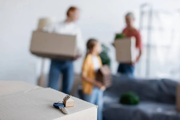 Foco seletivo da chave do novo apartamento perto de mulheres lésbicas e criança adotada em fundo embaçado — Fotografia de Stock