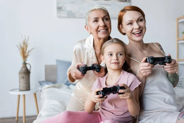 KYIV, UKRAINE - DECEMBER 8, 2021: Kid playing video game with mothers in bedroom — Stock Photo