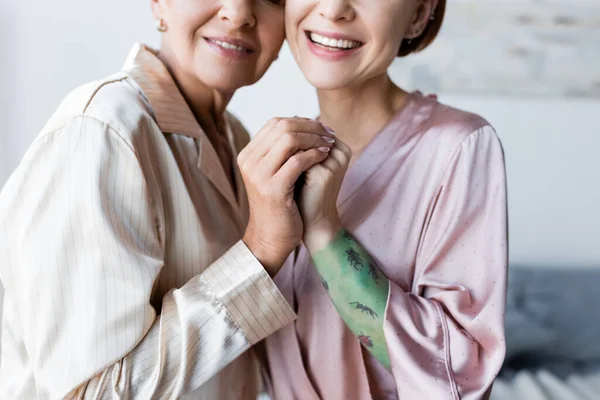 Vue recadrée du couple lesbien souriant tenant la main à la maison — Photo de stock
