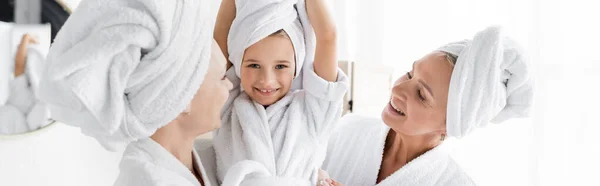 Lächelndes Mädchen im Handtuch, das in die Kamera neben Müttern zu Hause schaut, Banner — Stockfoto