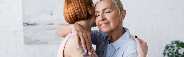 Mujer lesbiana abrazando novia en casa, pancarta - foto de stock