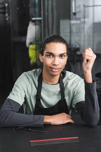 Jovem barbeiro afro-americano olhando para a câmera no salão de arrumação — Fotografia de Stock