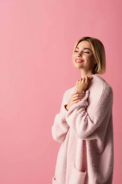 Счастливая молодая женщина в мягком кардигане изолированы на розовый — стоковое фото