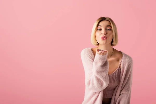 Giovane donna in morbido cardigan invio aria bacio isolato su rosa — Foto stock