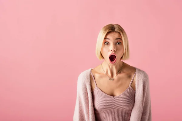 Conmocionado joven mujer en suave cárdigan mirando a la cámara aislada en rosa - foto de stock