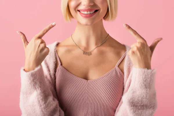 Обрезанный вид счастливой молодой женщины указывая пальцами на белые зубы изолированы на розовый — стоковое фото