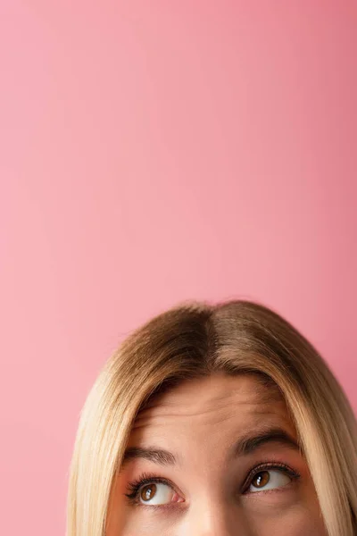 Vue recadrée de femme blonde fronçant les sourcils et regardant loin isolé sur rose — Photo de stock