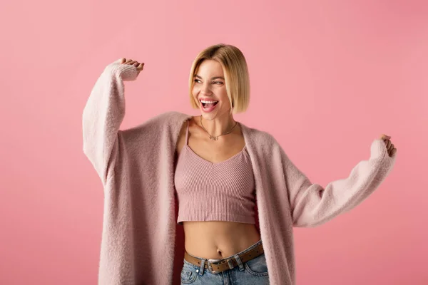 Positive junge Frau in weicher Strickjacke gestikuliert isoliert auf rosa — Stockfoto