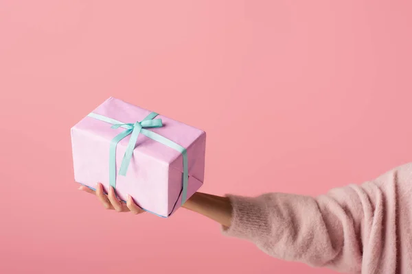 Vista recortada de la mujer joven sosteniendo envuelto caja de regalo aislado en rosa - foto de stock