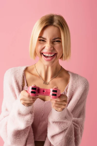 KYIV, UKRAINE - OCTOBER 29, 2021: позитивна жінка тримає джойстик і грає у відеоігри ізольовані на рожевому — стокове фото