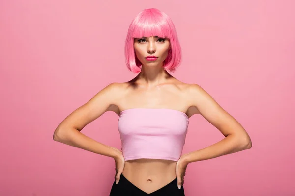 Giovane donna con frangia e capelli colorati posa con le mani sui fianchi isolato su rosa — Foto stock