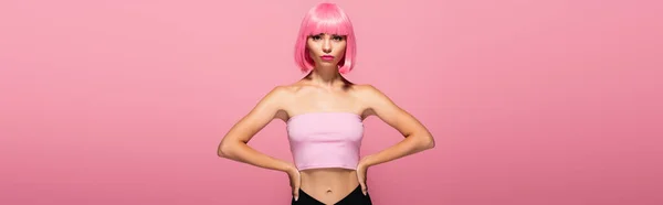 Jovem com franja e cabelos coloridos posando com as mãos sobre os quadris isolados em rosa, banner — Fotografia de Stock