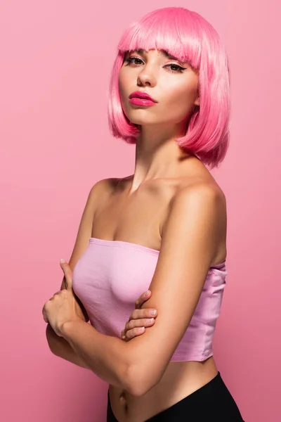Молода жінка з кольоровим волоссям дивиться на камеру ізольовано на рожевому — стокове фото