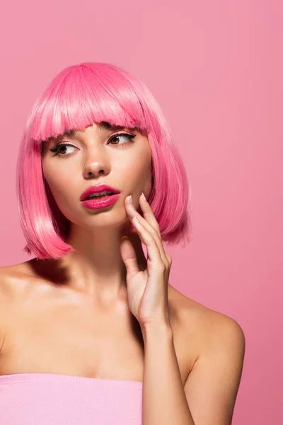 Mujer joven con el pelo de color y flequillo mirando hacia otro lado aislado en rosa - foto de stock
