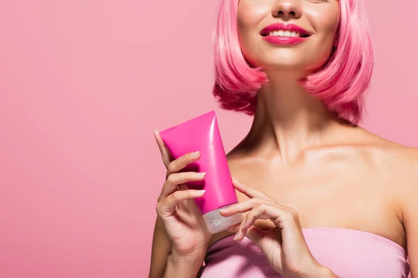 Vue recadrée de femme heureuse avec tube de maintien des cheveux colorés avec lotion isolée sur rose — Photo de stock