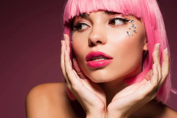 Junge Frau mit rosafarbenen Haaren und glänzenden Steinen im Gesicht, die wegschauen auf dunkelviolett — Stockfoto