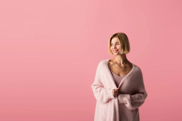 Довольная молодая женщина в кардигане изолированы на розовый — стоковое фото