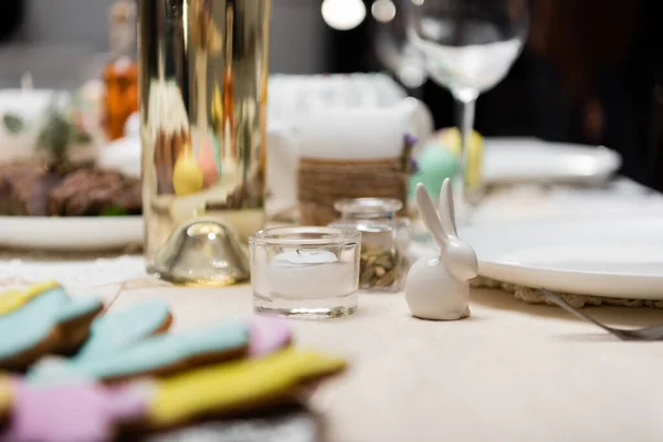 Foyer sélectif de lapin décoratif et de bougie près de biscuits flous et bouteille de vin — Photo de stock