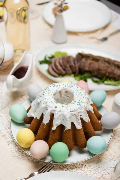 Delicioso bolo de Páscoa com ovos pintados perto de molho e carne frita no fundo borrado — Fotografia de Stock