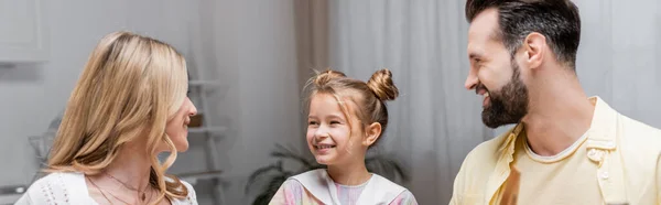 Alegre pareja mirando sonriente hija en casa, bandera - foto de stock