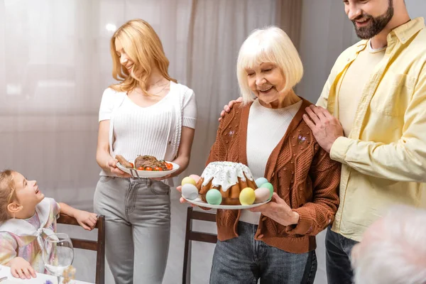 Lächelnde Frauen mit Osterkuchen und gebratenem Fleisch beim traditionellen Osteressen — Stockfoto