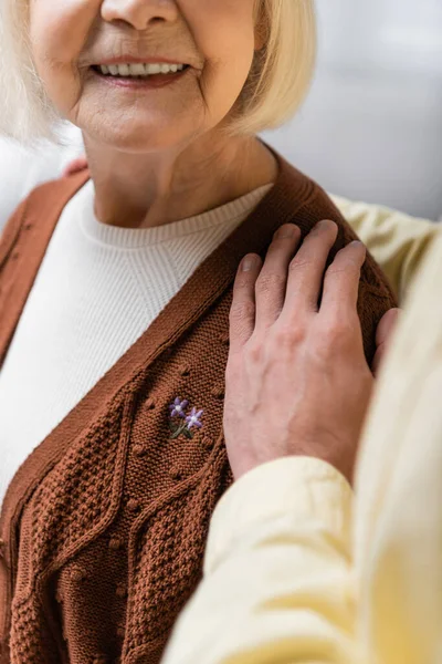 Cropped view of senior man embracing smiling wife on blurred foreground — Stock Photo