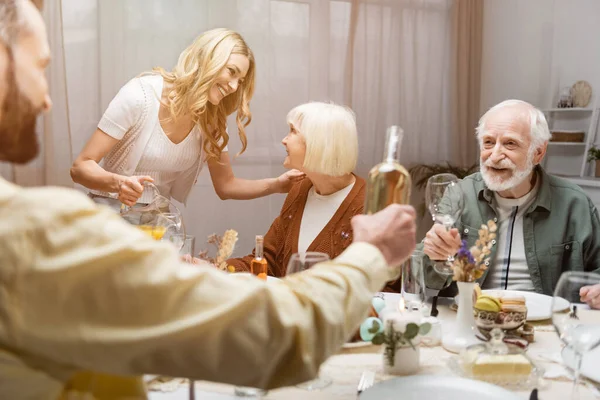 Man holding bottle of wine during easter dinner with senior parents — Stock Photo