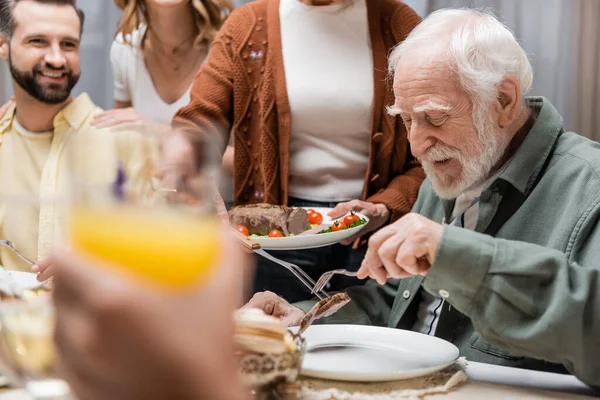 Senior woman serving fried meat during easter dinner with family — Stock Photo