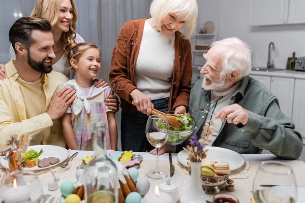 Glückliche Frau hält beim festlichen Abendessen Gemüsesalat neben Seniorin — Stockfoto