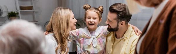 Menina animado abraçando pais felizes em primeiro plano borrado, banner — Fotografia de Stock