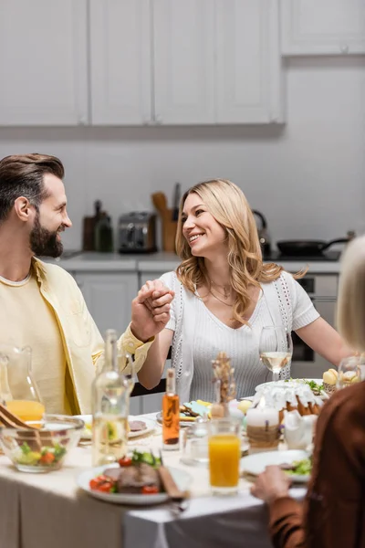 Happy couple holding hands and looking at each other while celebrating easter at home — Stock Photo