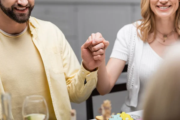 Cropped view of cheerful couple holding hands during easter celebration — Stock Photo