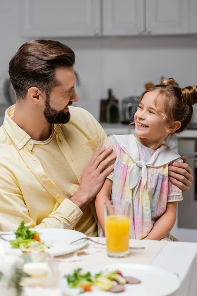 Happy man embracing preteen daughter during easter dinner at home — Stock Photo