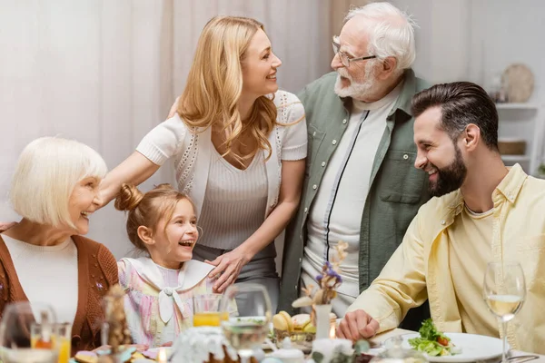 Senior man talking to smiling woman during easter celebration with family — Stock Photo