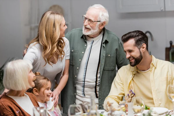 Senior man talking to adult daughter during easter dinner with family — Stock Photo