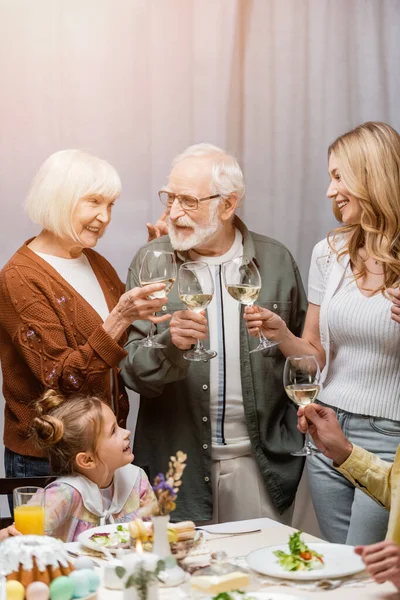 Happy family clinking wine glasses during easter celebration — Stock Photo