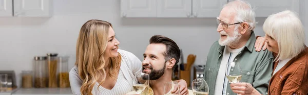 Alegre familia sosteniendo copas de vino mientras celebra la Pascua en casa, pancarta - foto de stock