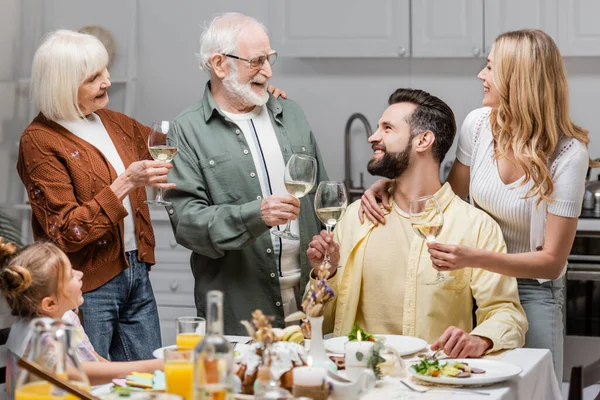 Famiglia eccitata che tiene bicchieri di vino mentre brinda durante la cena di Pasqua — Foto stock